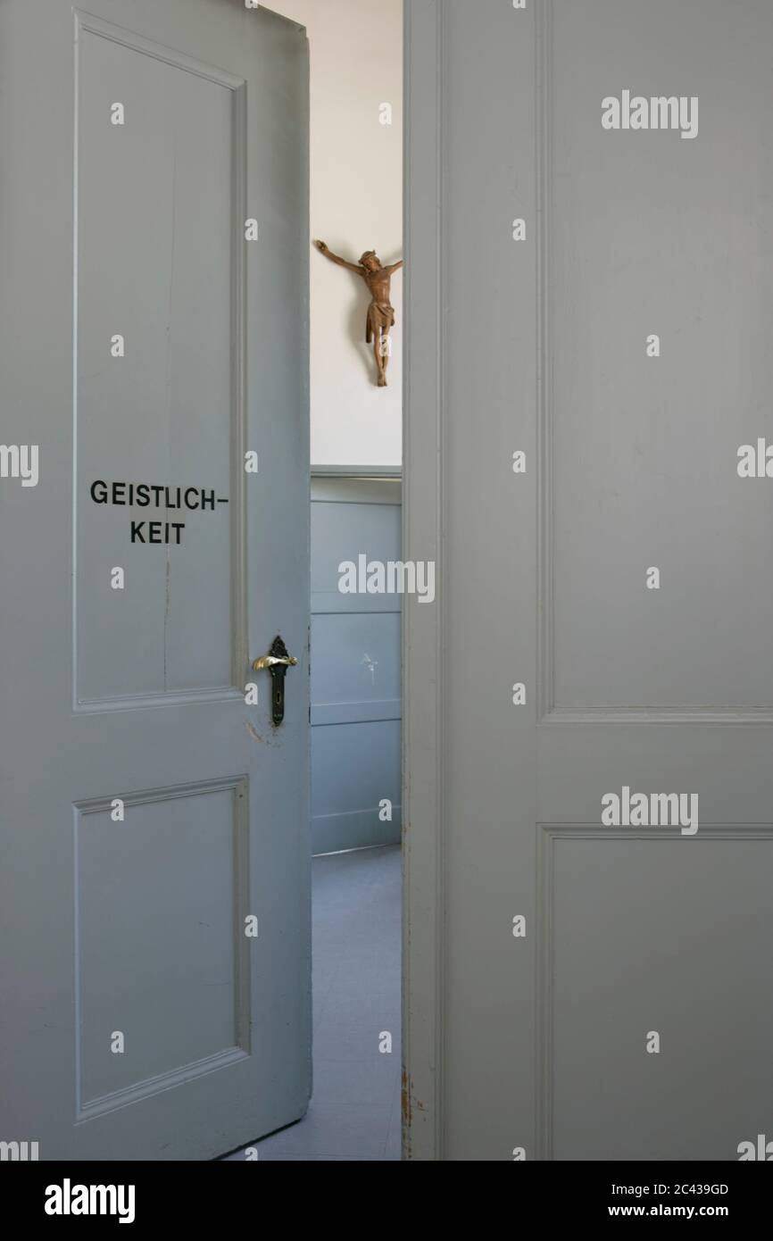 Porte blanche avec inscription du clergé ouvre la salle avec crucifix sur le mur Banque D'Images