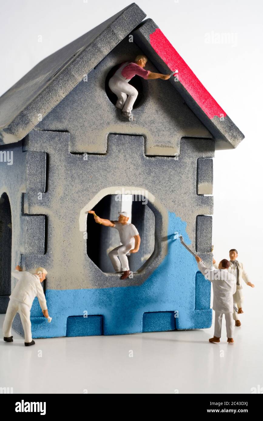 Des figurines de peintre peignent un modèle de maison Banque D'Images