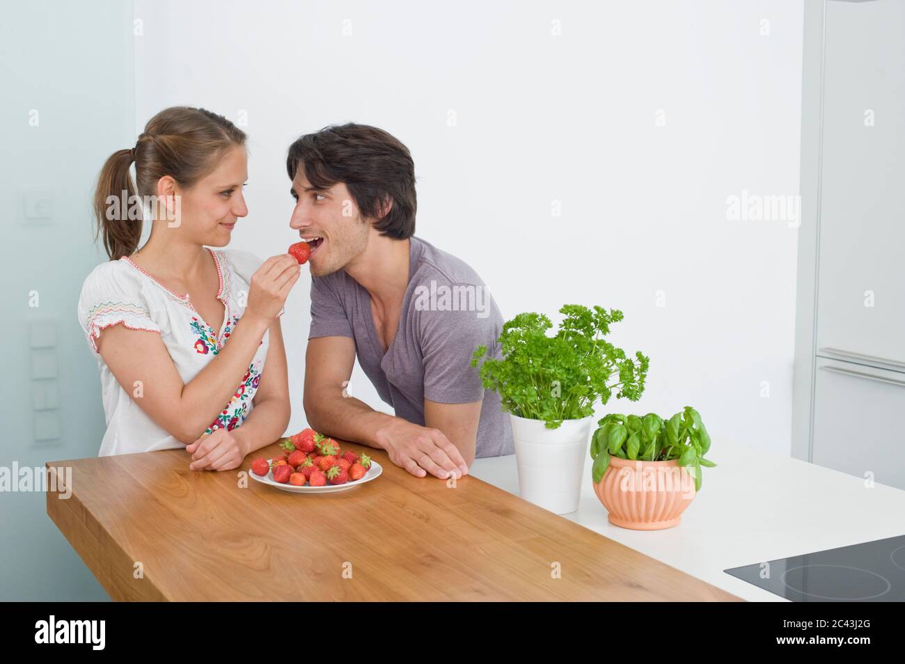 Un jeune couple dans la cuisine mange des fraises, Munich, Bavière, Allemagne Banque D'Images