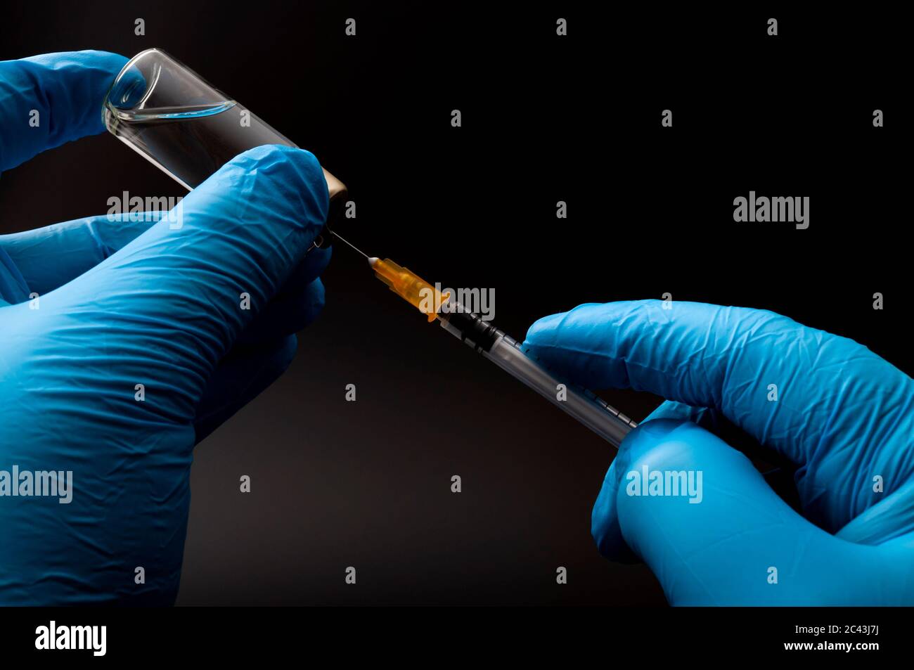 Injection d'insuline, grippe jab ou traiter la maladie avec un thème de concept d'injection avec les mains du médecin ou de l'infirmière portant des gants chirurgicaux bleus en latex remplissant un système Banque D'Images