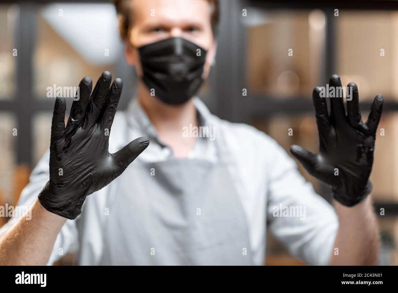 Portrait d'un vendeur en gants de protection et masque facial montrant les  mains dans le magasin ou le café. Concept de nouvelles règles pour les  entreprises en cas de pandémie Photo Stock -