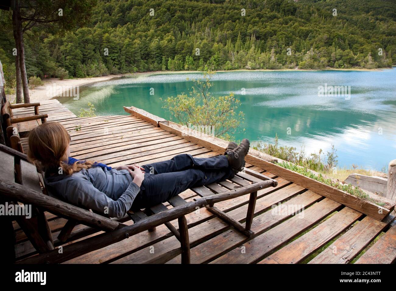 Femme couché sur une chaise longue en bois sur le lac, Patagonie, Chili Banque D'Images