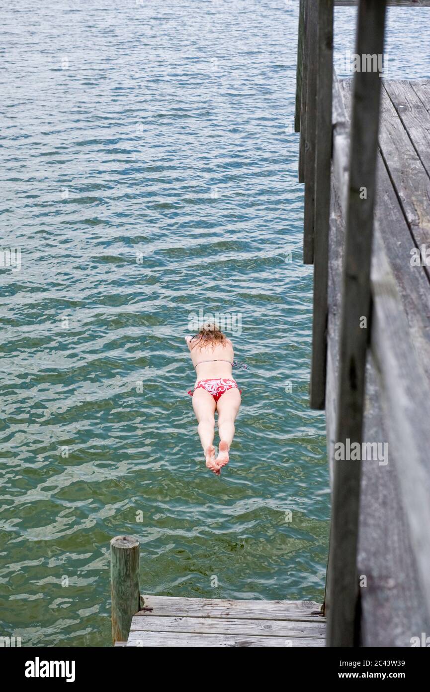 Femme saute d'une jetée dans l'eau, fort Walton Beach, Floride, États-Unis Banque D'Images