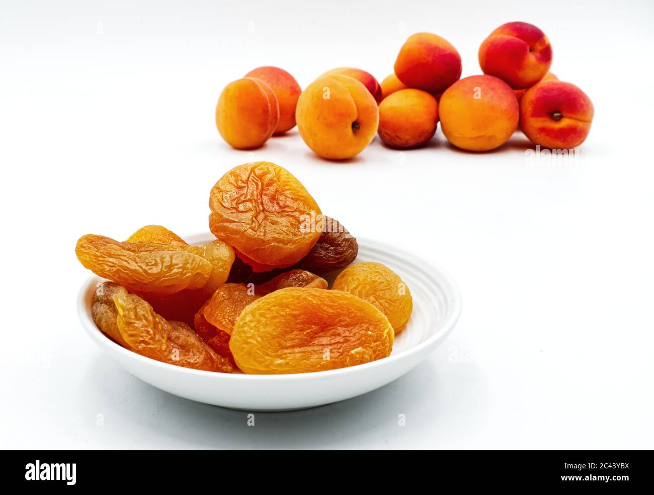 Abricots séchés dans un bol isolé sur blanc. Mise au point sélective Banque D'Images