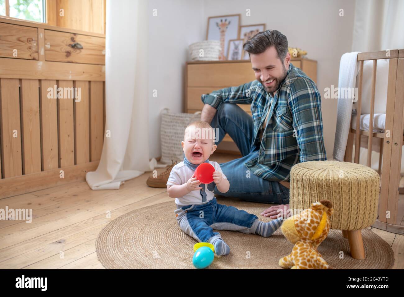 Père dans une chemise à carreaux souriant tandis que son petit fils ne regarde pas satisfait Banque D'Images