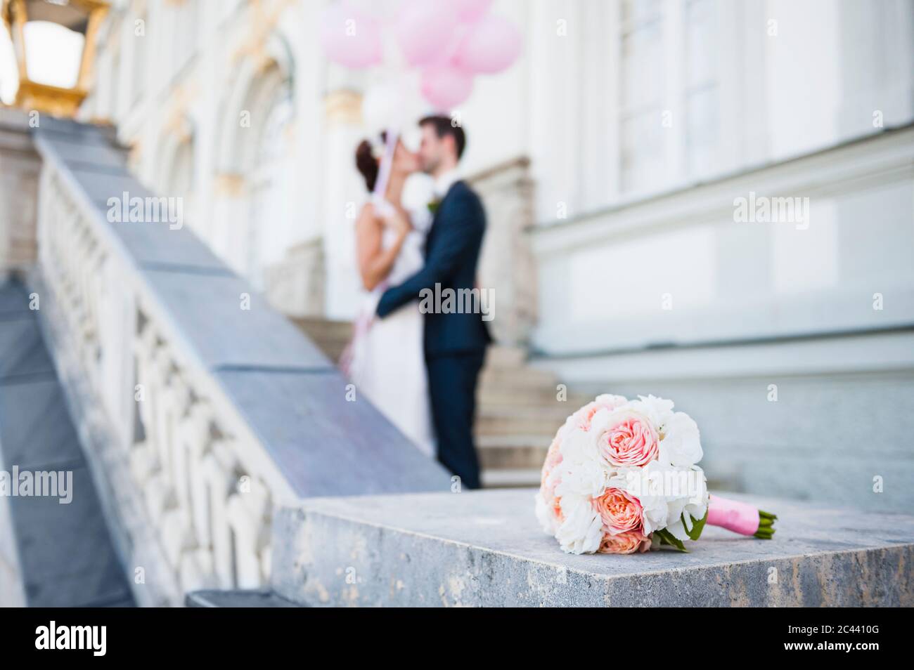 Bouquet de mariée avec couple de mariée embrassant en arrière-plan Banque D'Images