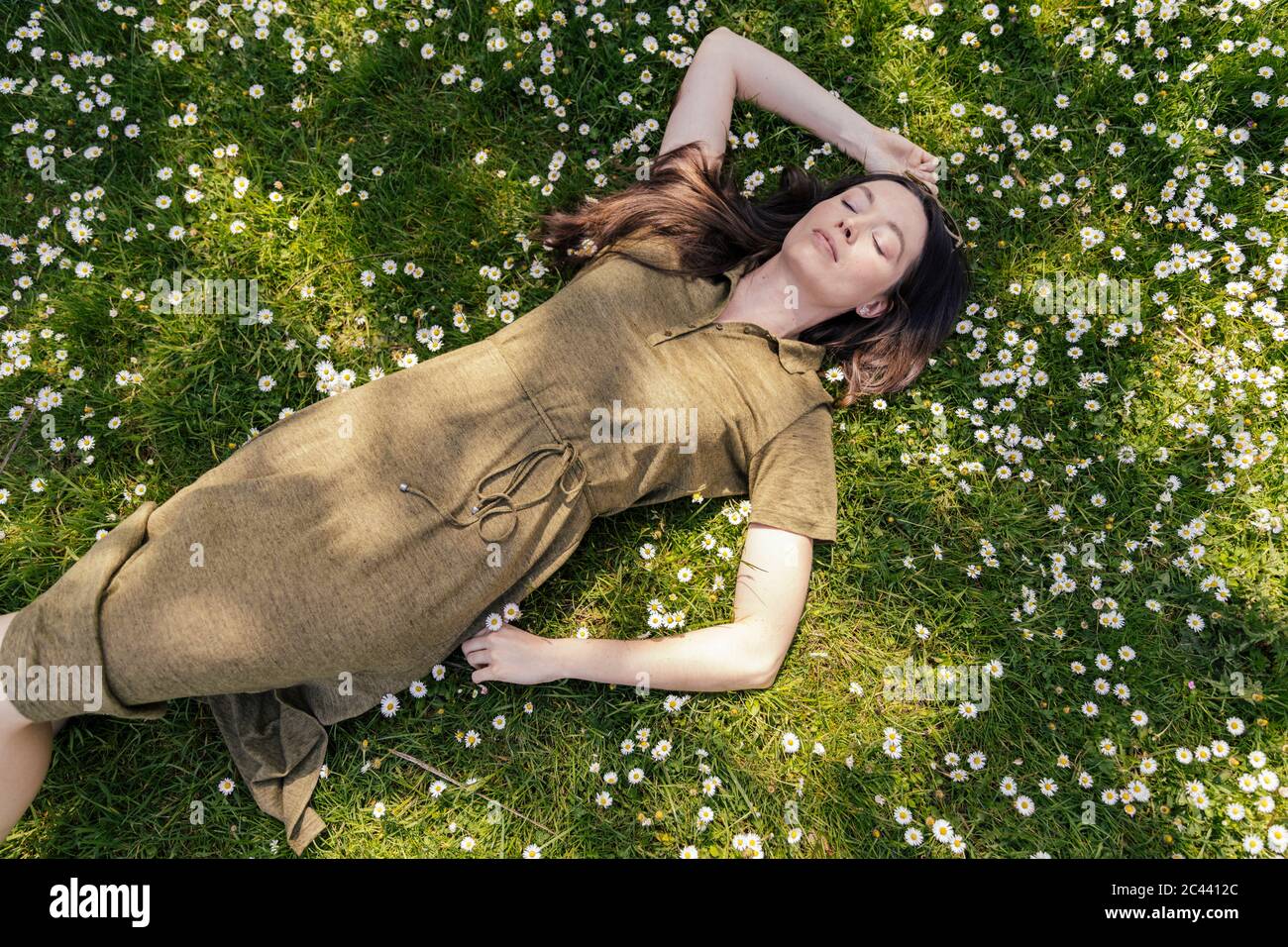 Femme appréciant son temps libre en étant couché sur l'herbe avec des pâquerettes Banque D'Images