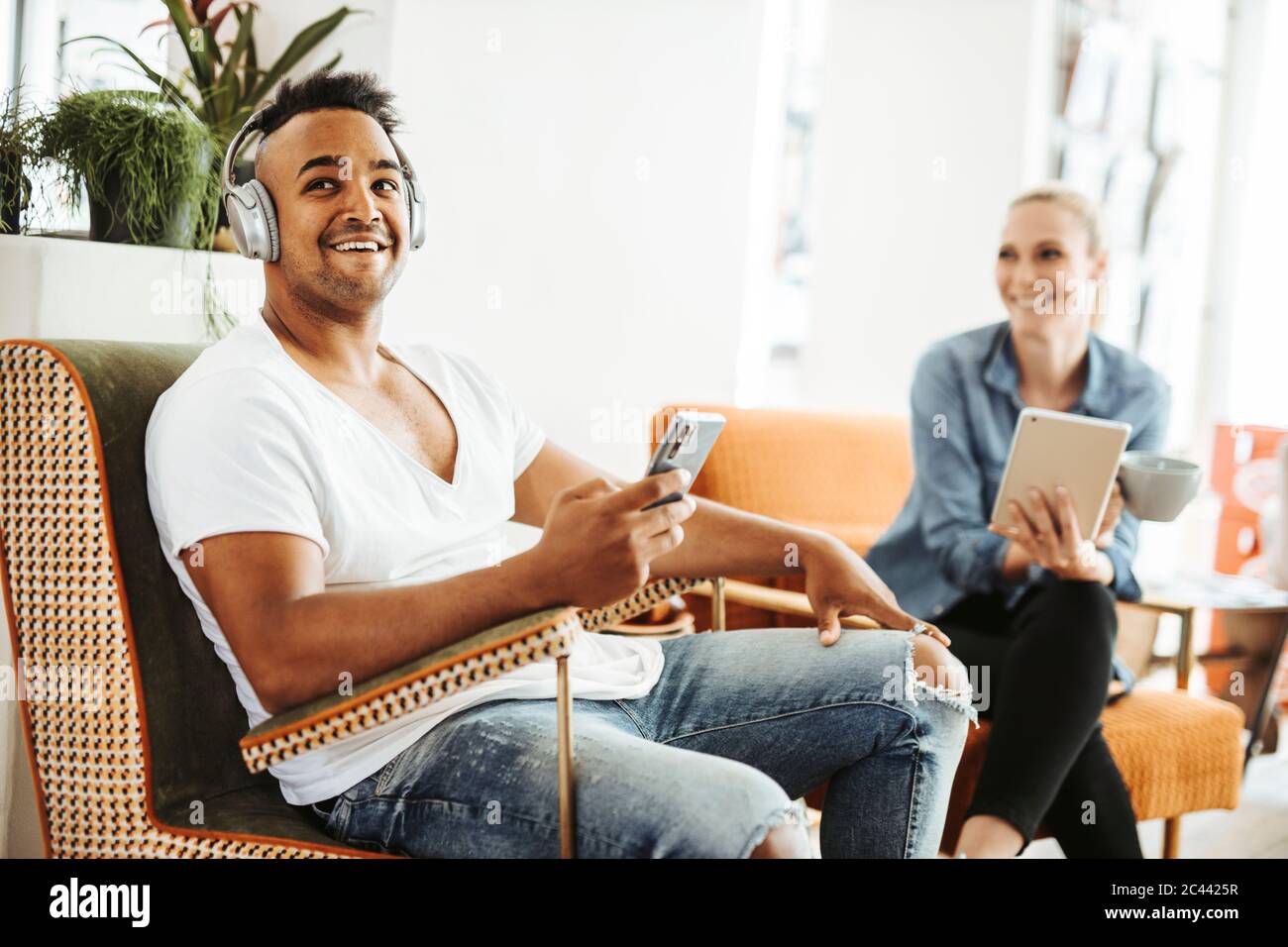 Homme et femme se détendant avec des appareils électroniques Banque D'Images