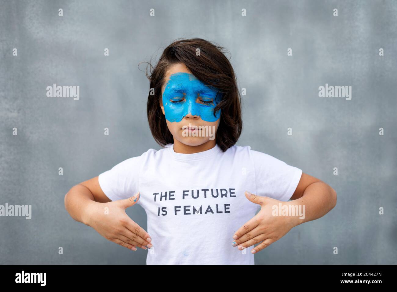 Portrait d'un garçon avec masque bleu peint sur son visage portant un t-shirt avec l'empreinte « The future is female » Banque D'Images
