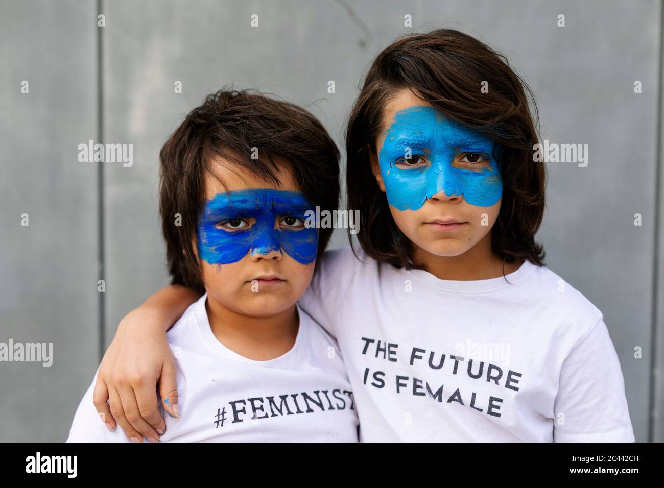 Portrait de deux frères avec masques bleus peints sur leur visage portant des t-shirts avec des empreintes féministes Banque D'Images