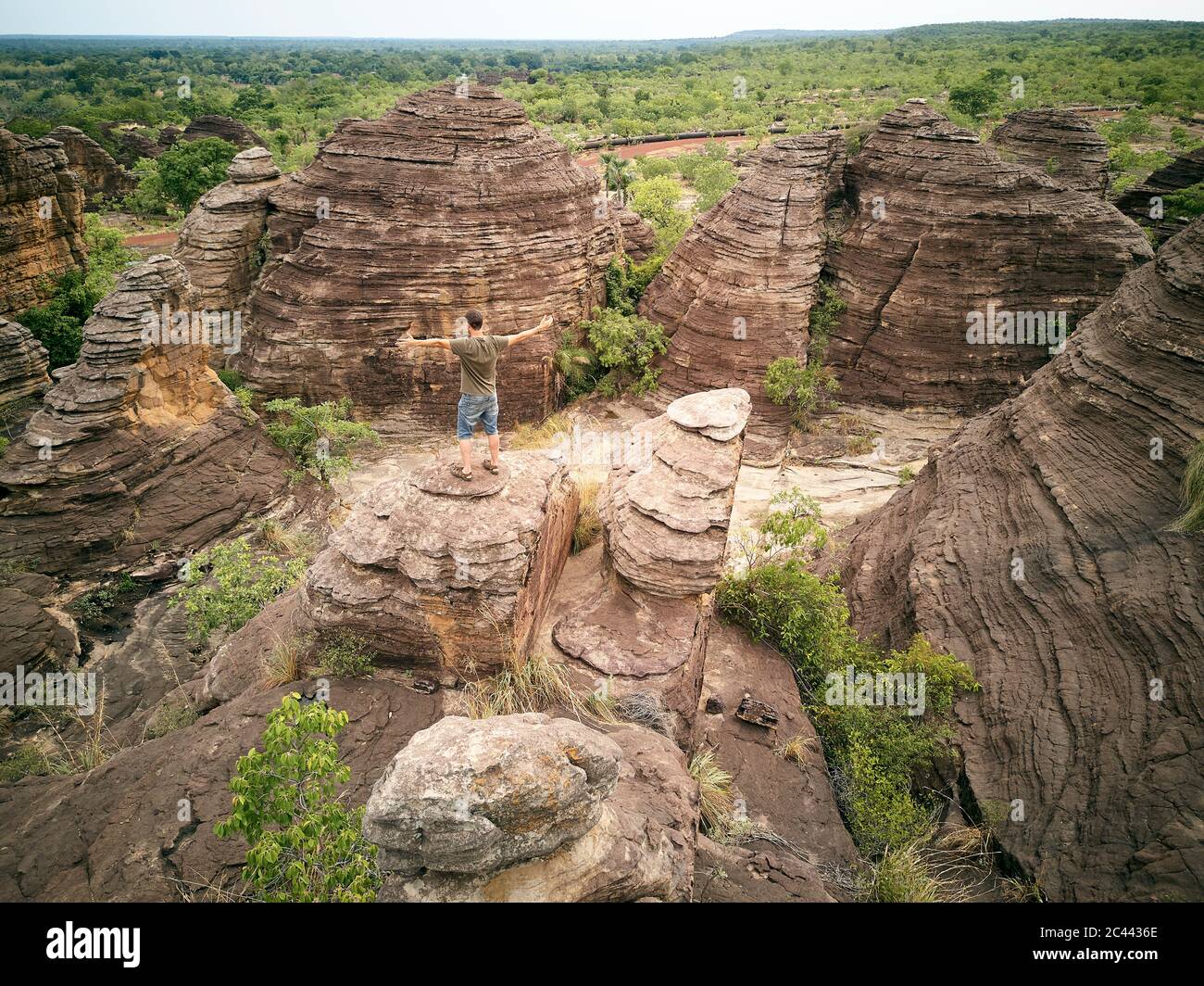Burkina Faso, Homme aux bras étirés sur le haut de la roche à dômes de Fabedougou Banque D'Images