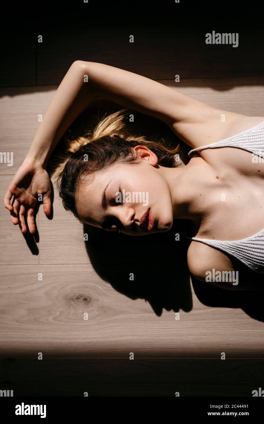 Directement au-dessus de la vue de la femme avec les yeux fermés, allongé sur un plancher de bois franc à la maison Banque D'Images