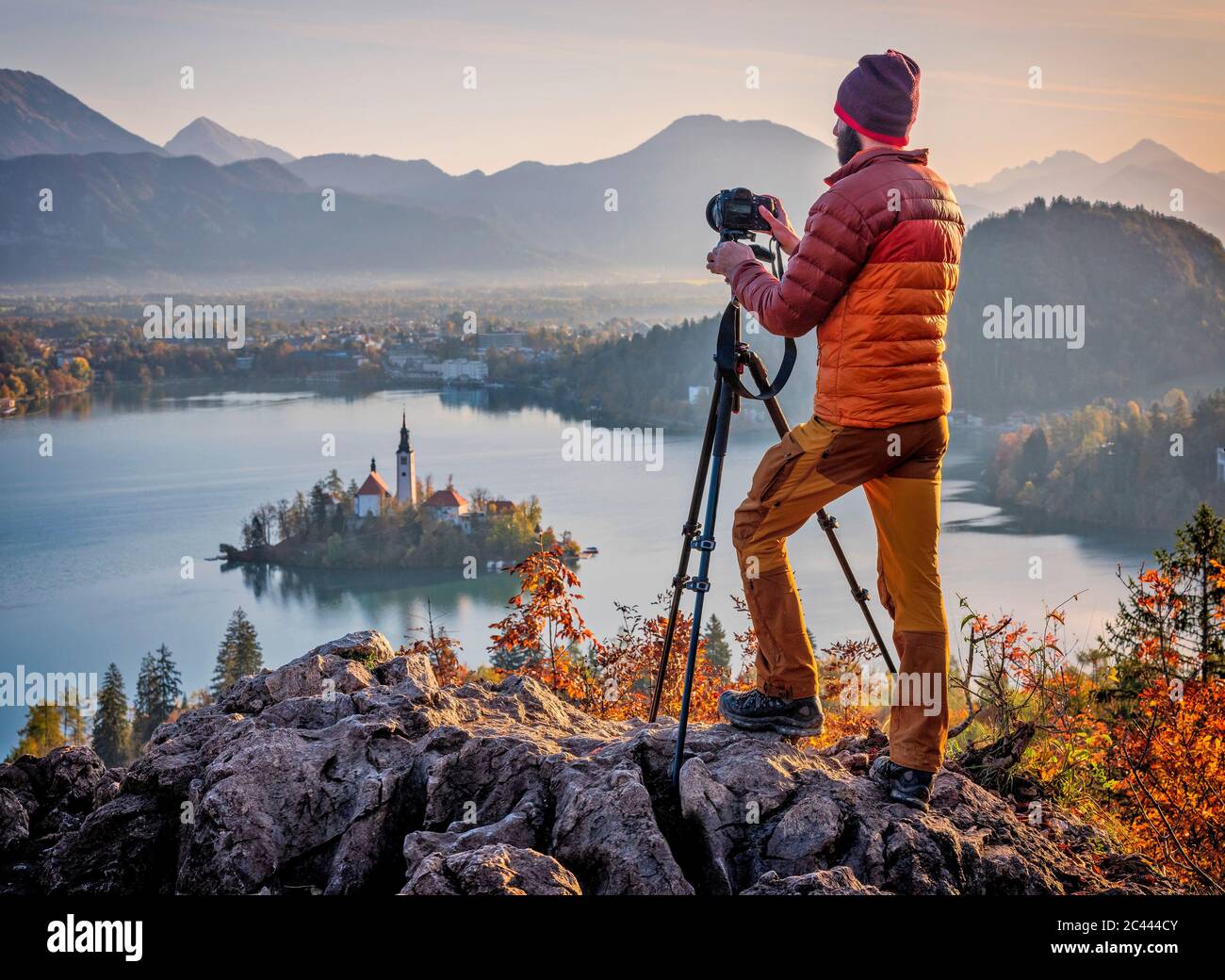 Slovénie, haute-Carniola, Bled, Homme photographiant l'île Bled et Eglise de pèlerinage de l'Assomption de Maria à l'aube brumeuse Banque D'Images