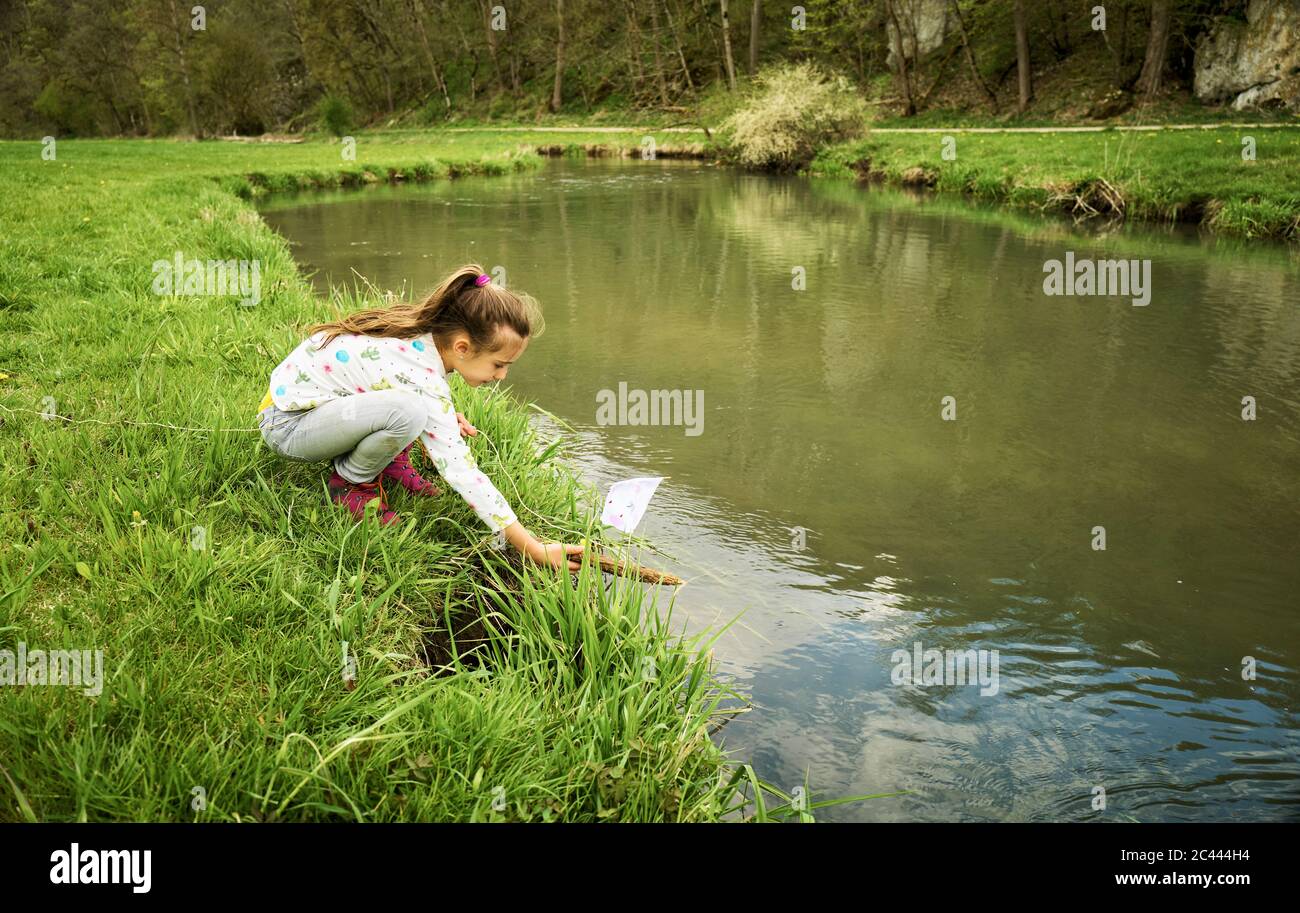 Fille met son bateau à jouets auto-fabriqué dans la rivière en forêt Banque D'Images