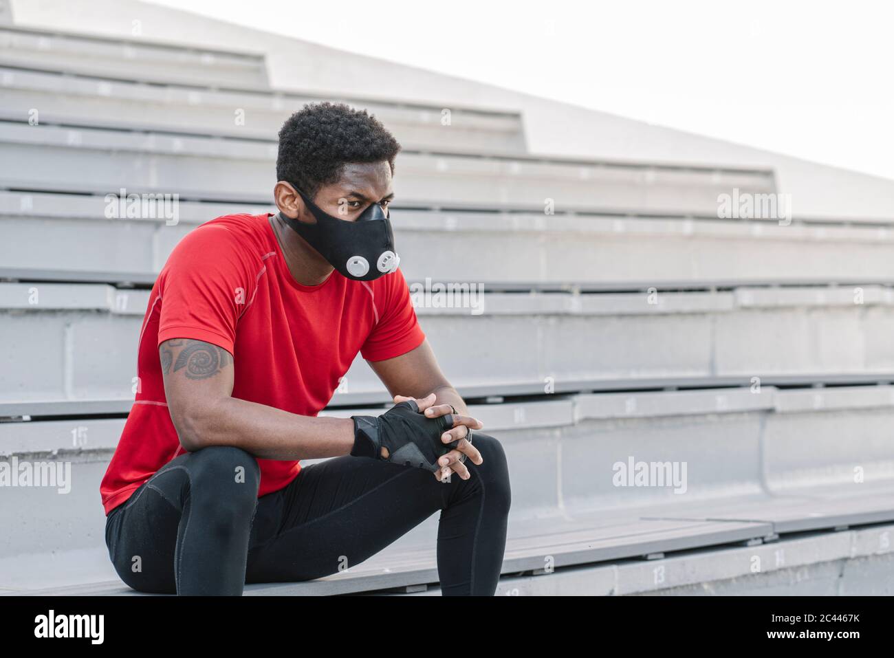 Sportif portant un masque facial assis dans les escaliers Banque D'Images