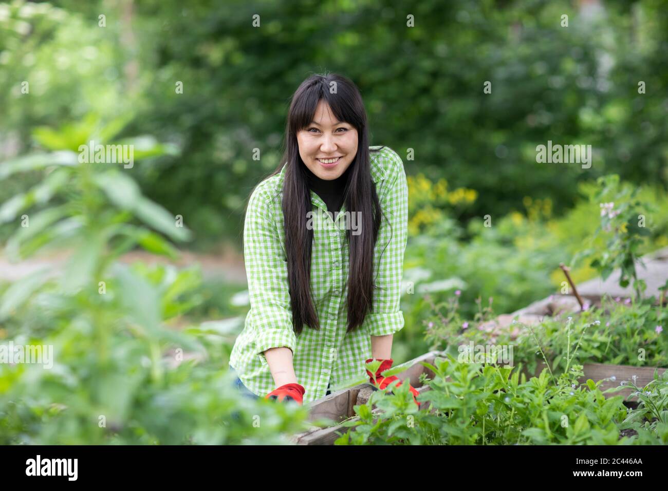 Femme souriante regardant la caméra dans un jardin urbain Banque D'Images