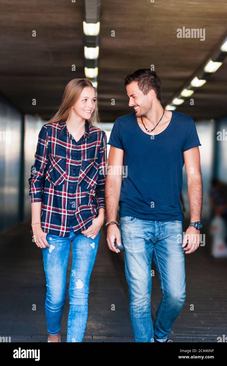 Portrait d'un jeune couple marchant ensemble dans un passage inférieur en regardant l'un l'autre Banque D'Images Portrait d'un jeune couple marchant ensemble dans un passage inférieur en regardant l'un l'autre Banque D'Images