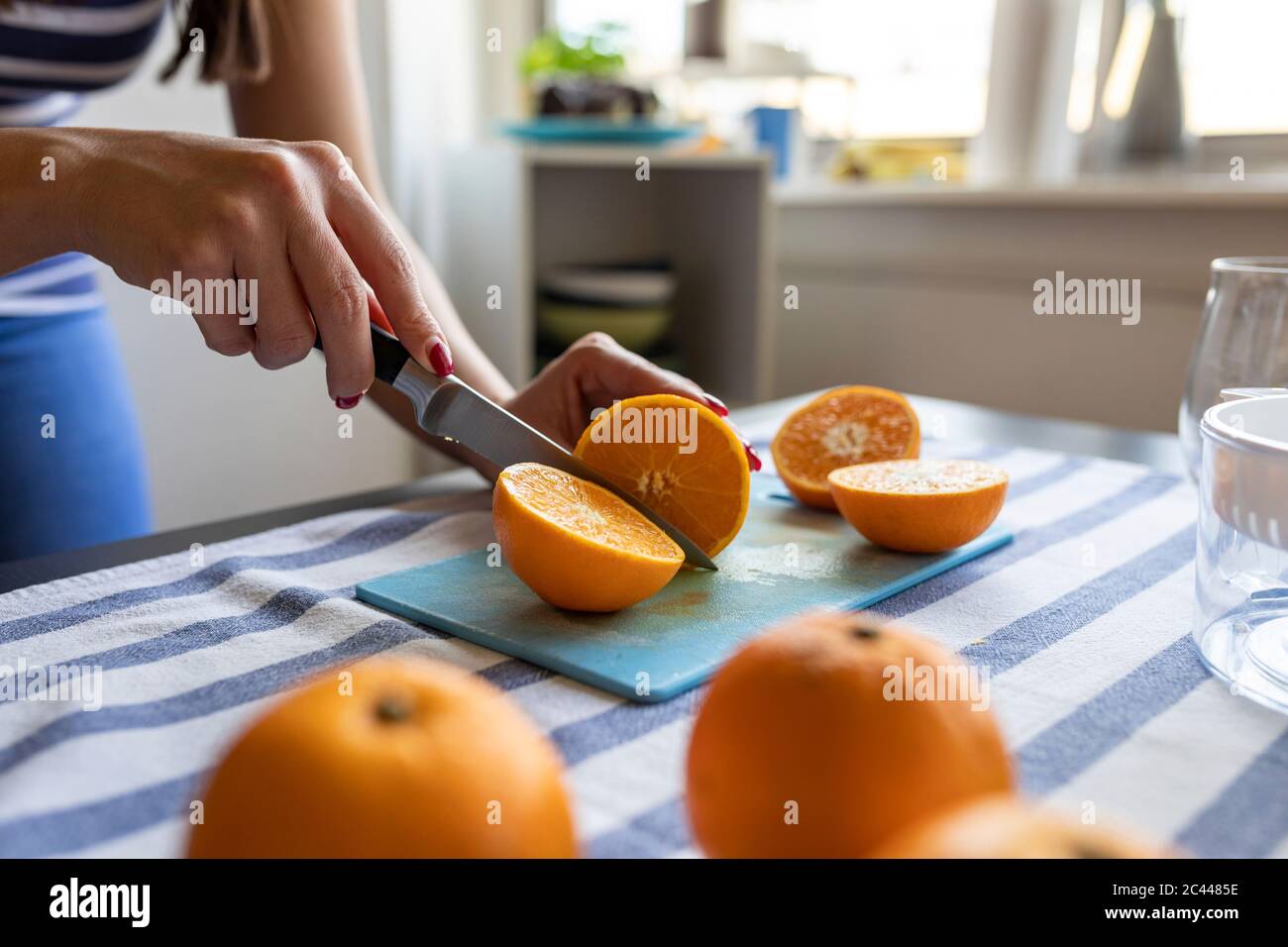 Femme en tranches d'oranges fraîches pour obtenir du jus d'orange fraîchement pressé Banque D'Images