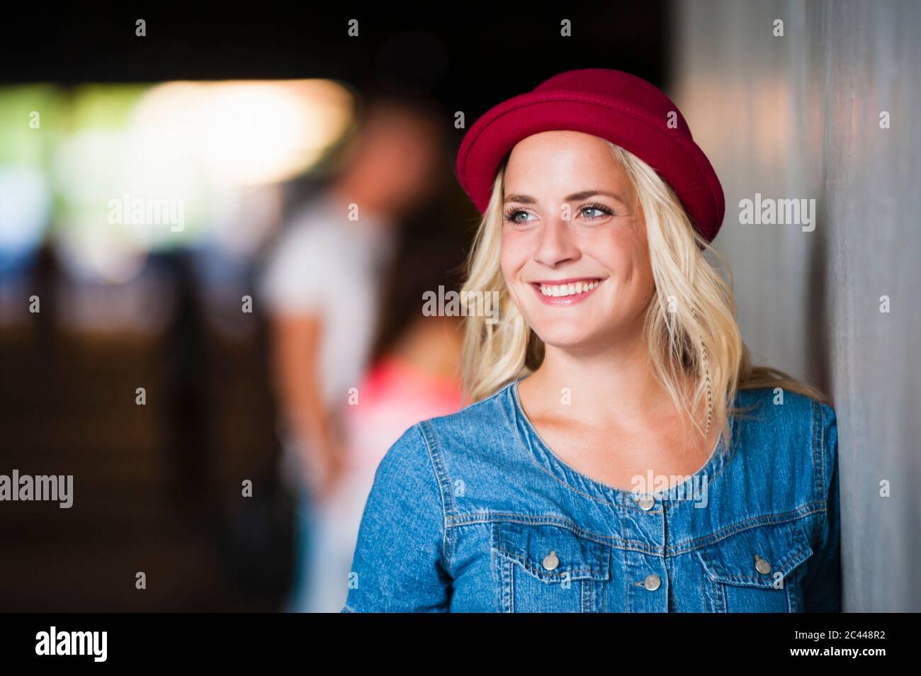 Portrait d'une jeune femme heureuse portant un chapeau rouge appuyé contre le mur Banque D'Images