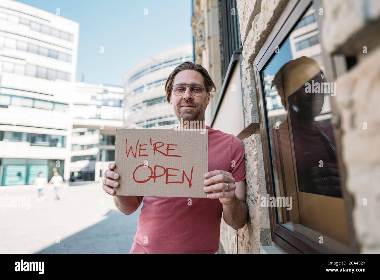 Un commerçant tient du carton avec l'annonce d'ouverture dans la ville Banque D'Images