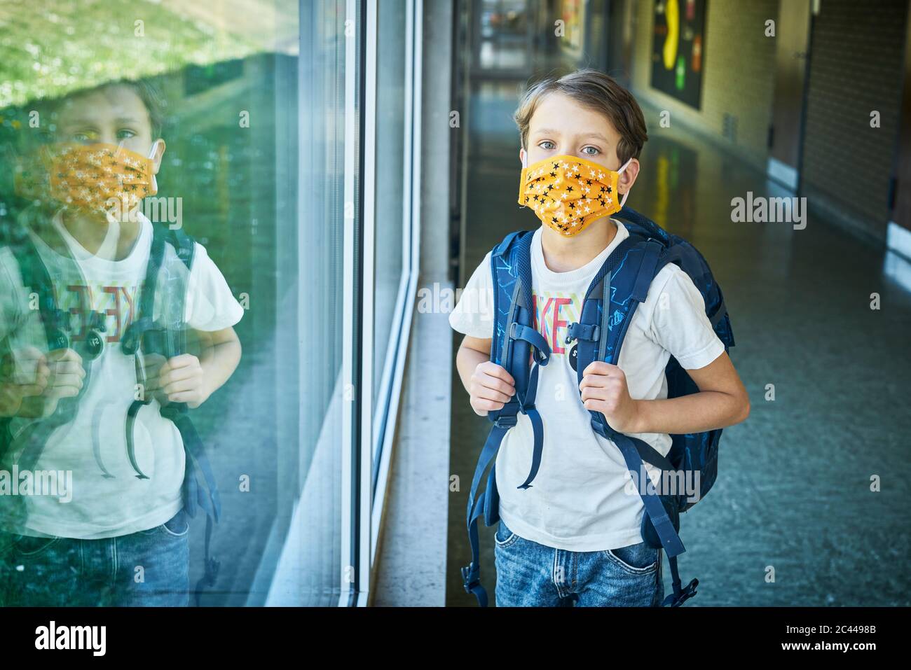 Garçon portant un masque à l'école, miroir dans la fenêtre Banque D'Images