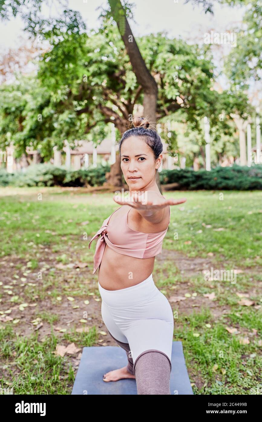 Femme de taille moyenne pratiquant le yoga sur tapis dans le parc Banque D'Images