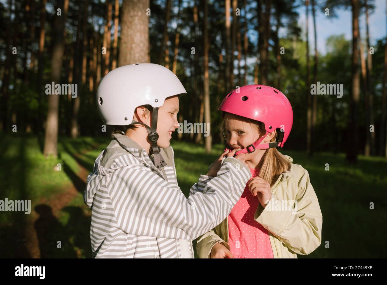 Happy boy fixation casque vélo pour fille en forêt Banque D'Images