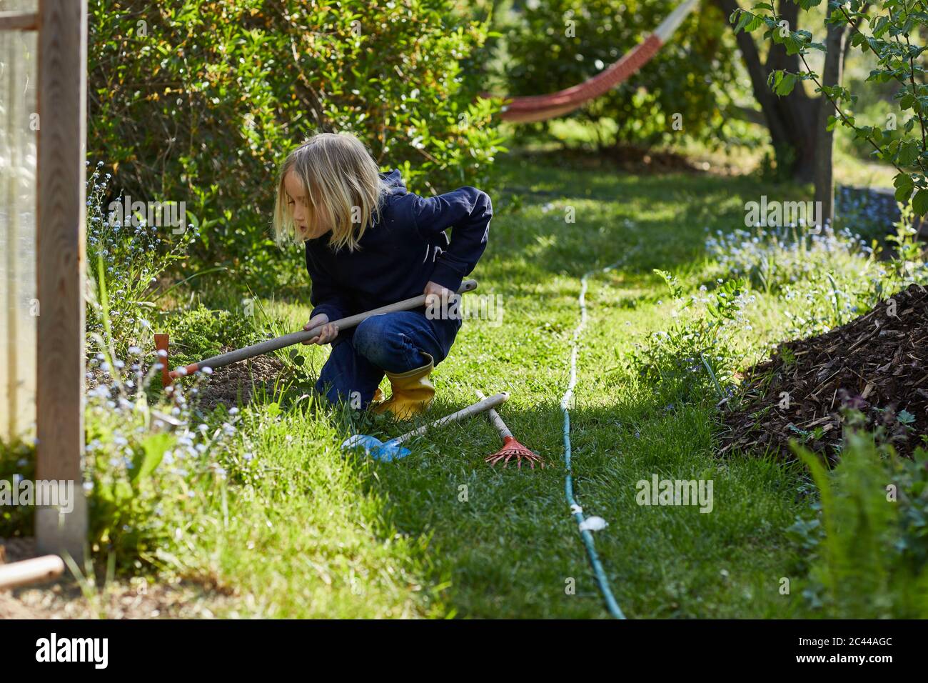 Fille travaillant avec une houe dans le jardin d'allotement Banque D'Images