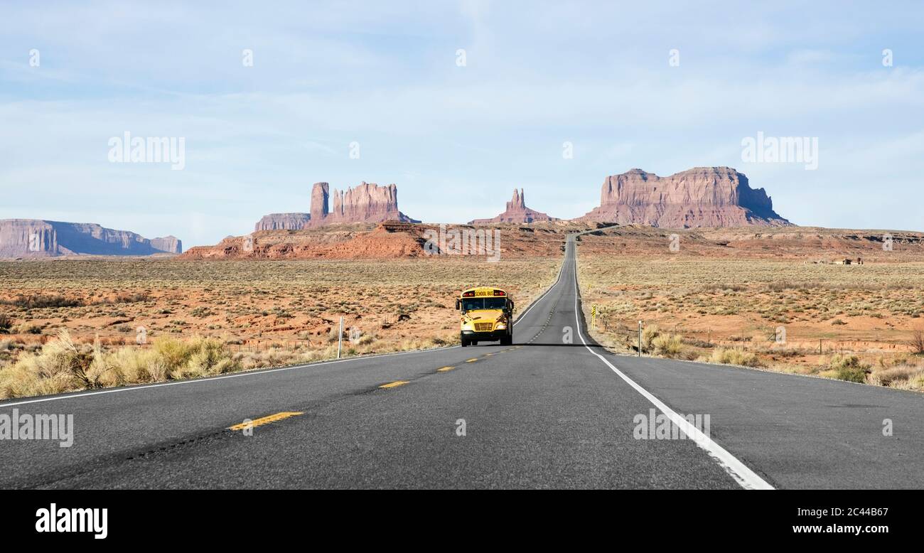 Bus scolaire sur la route du désert au célèbre Monument Valley Tribal Park contre le ciel, Utah, États-Unis Banque D'Images