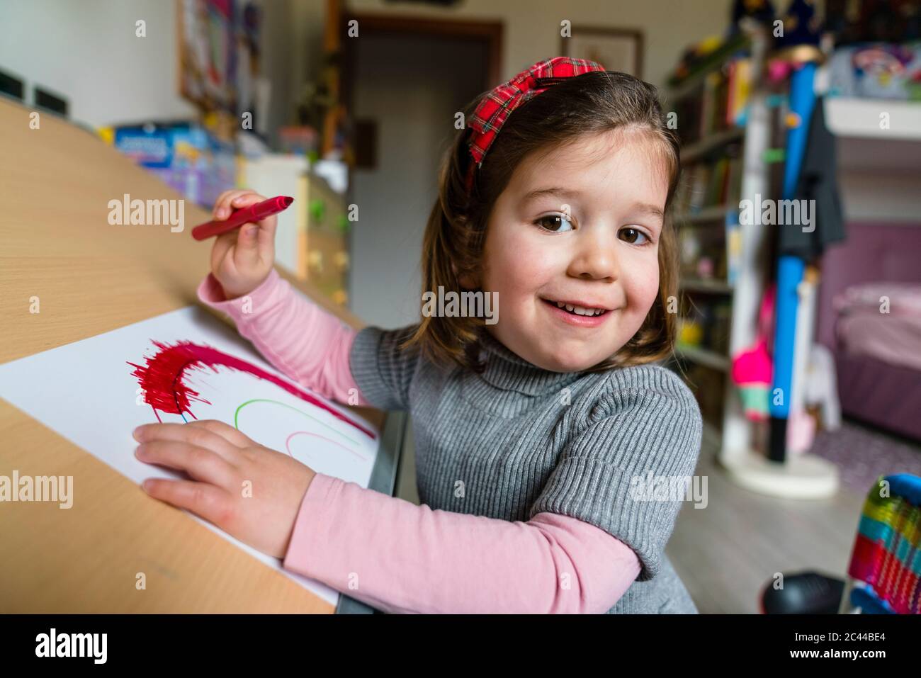 Portrait de la jolie fille souriante colorant sur papier à la maison Banque D'Images