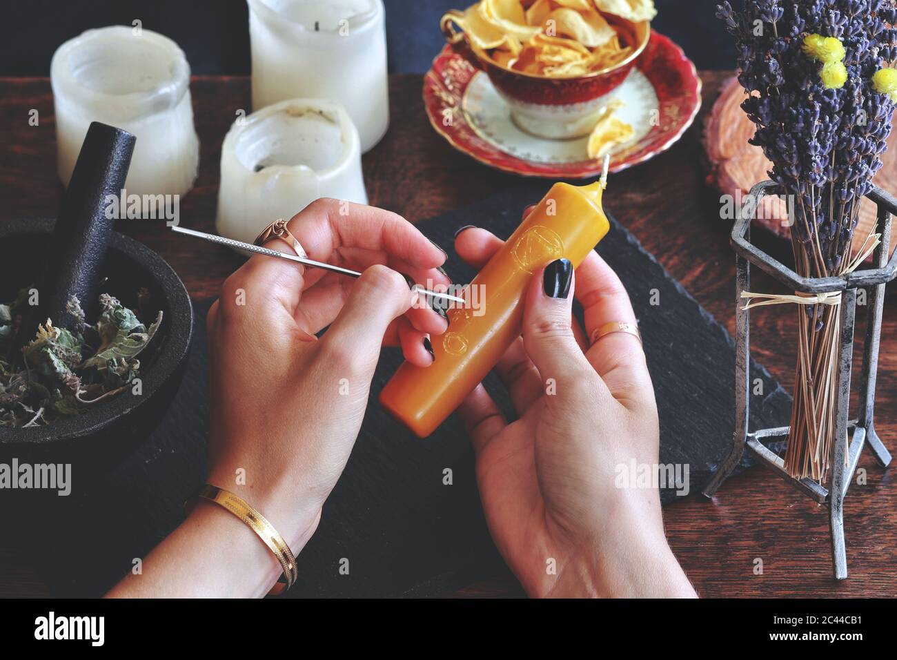 Wiccan symbole et sigles de sorcière sculptant sur le chandelier jaune de couleur or à son autel. Tenir la bougie dans les mains. Éléments qui démangent sur un arrière-plan flou Banque D'Images