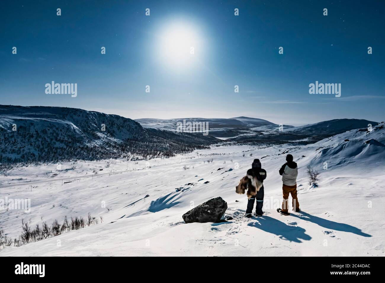 Randonneurs en raquettes debout dans le paysage d'hiver dans la nuit polaire, Kilpisjaervi, Enontekioe, Finlande Banque D'Images