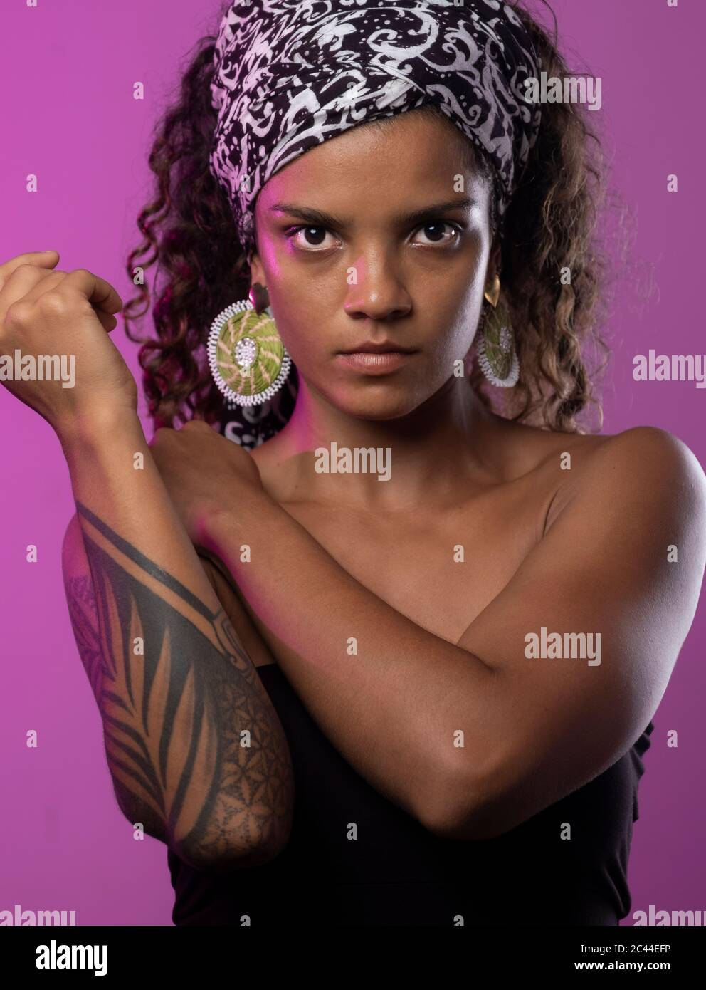Portrait d'une jeune femme sérieuse avec bras tatoué sur fond violet Banque D'Images