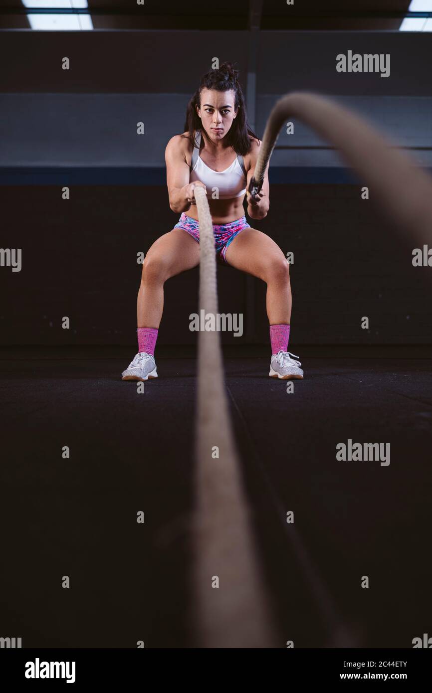 Jeune femme exerçant avec des cordes de bataille à la salle de gym Banque D'Images