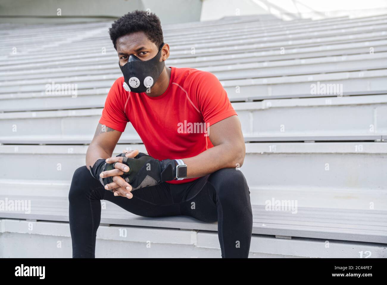 Sportif portant un masque facial assis dans les escaliers Banque D'Images