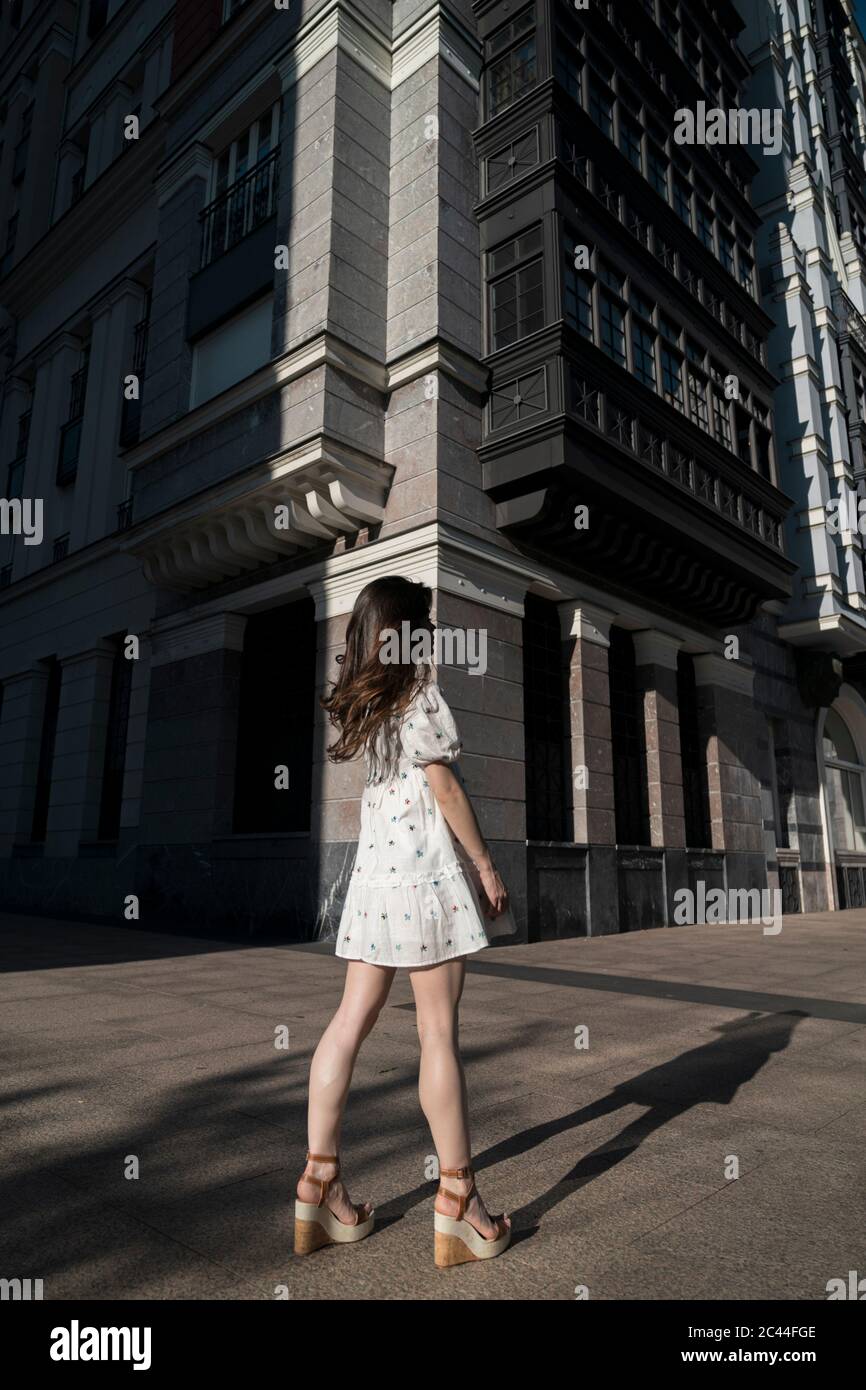 Jeune femme en robe blanche sur la rue de la ville pendant la journée ensoleillée Banque D'Images
