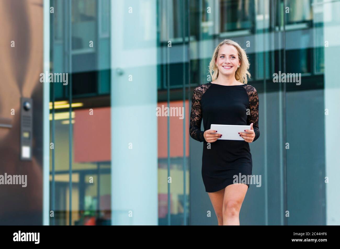 Portrait d'une jeune femme d'affaires heureuse avec tablette numérique portant une mini robe noire Banque D'Images