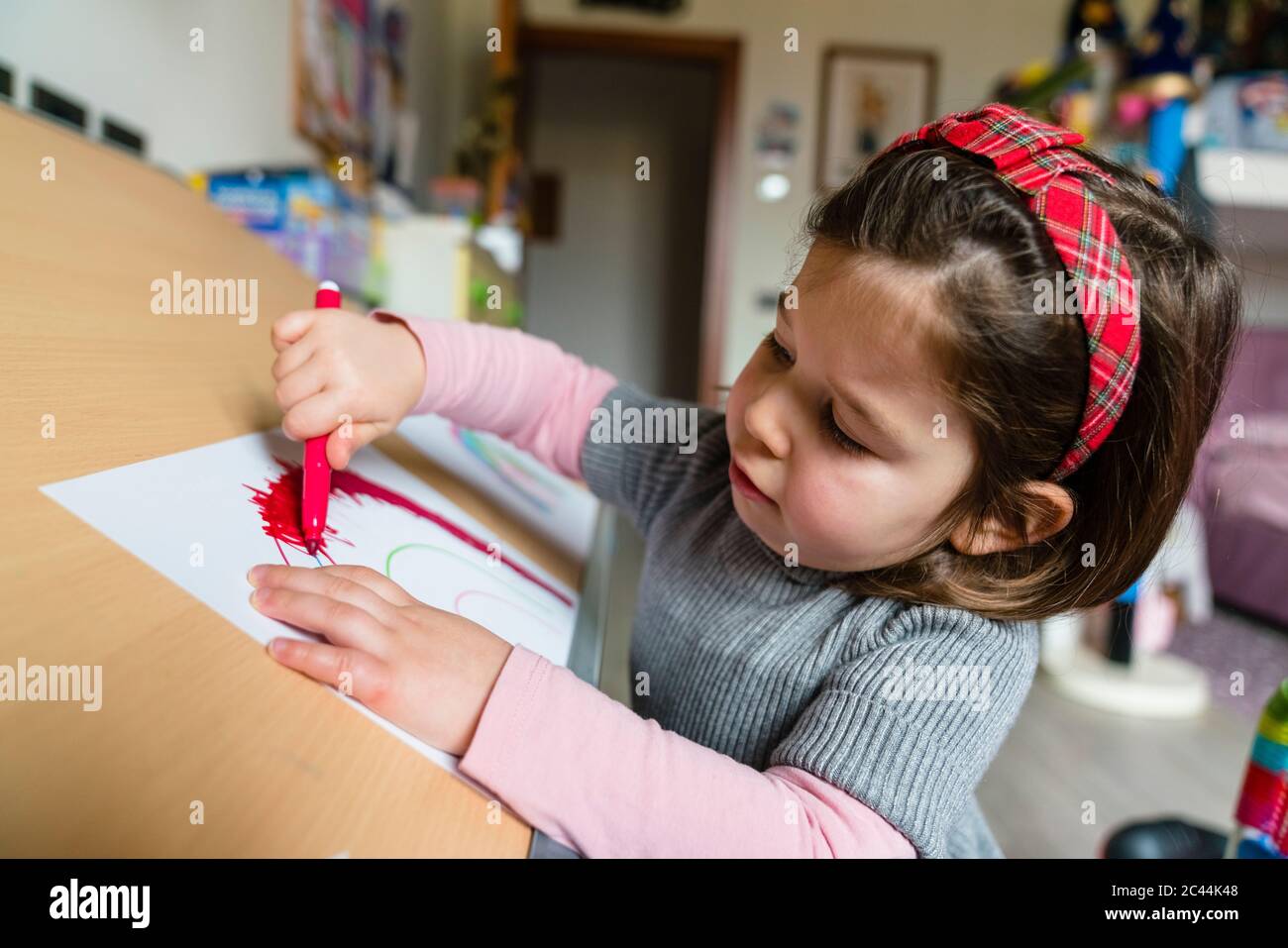 Adorable petite fille dessin sur papier à la maison Banque D'Images