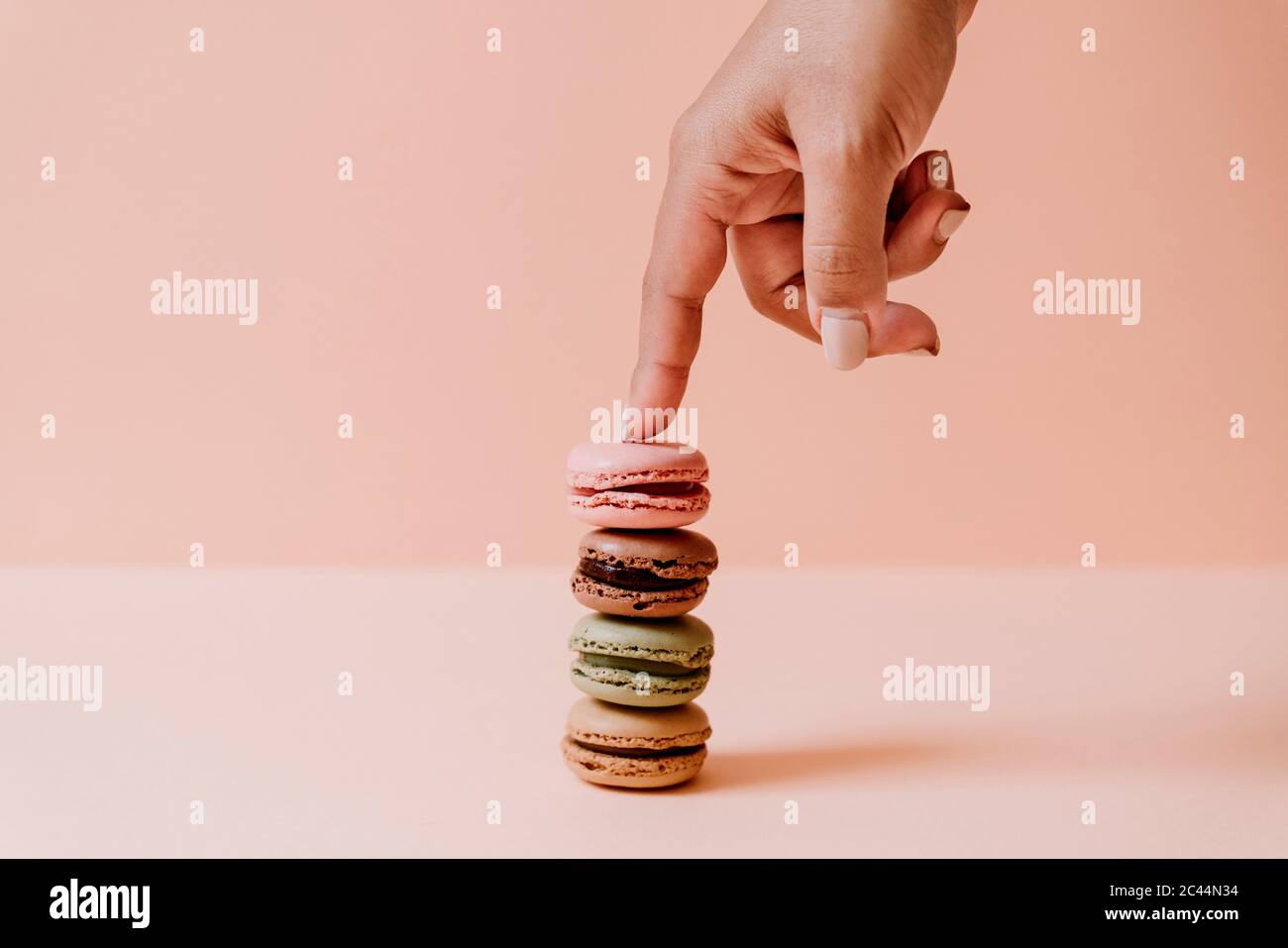 La main féminine de toucher pile de macarons sur fond rose Banque D'Images