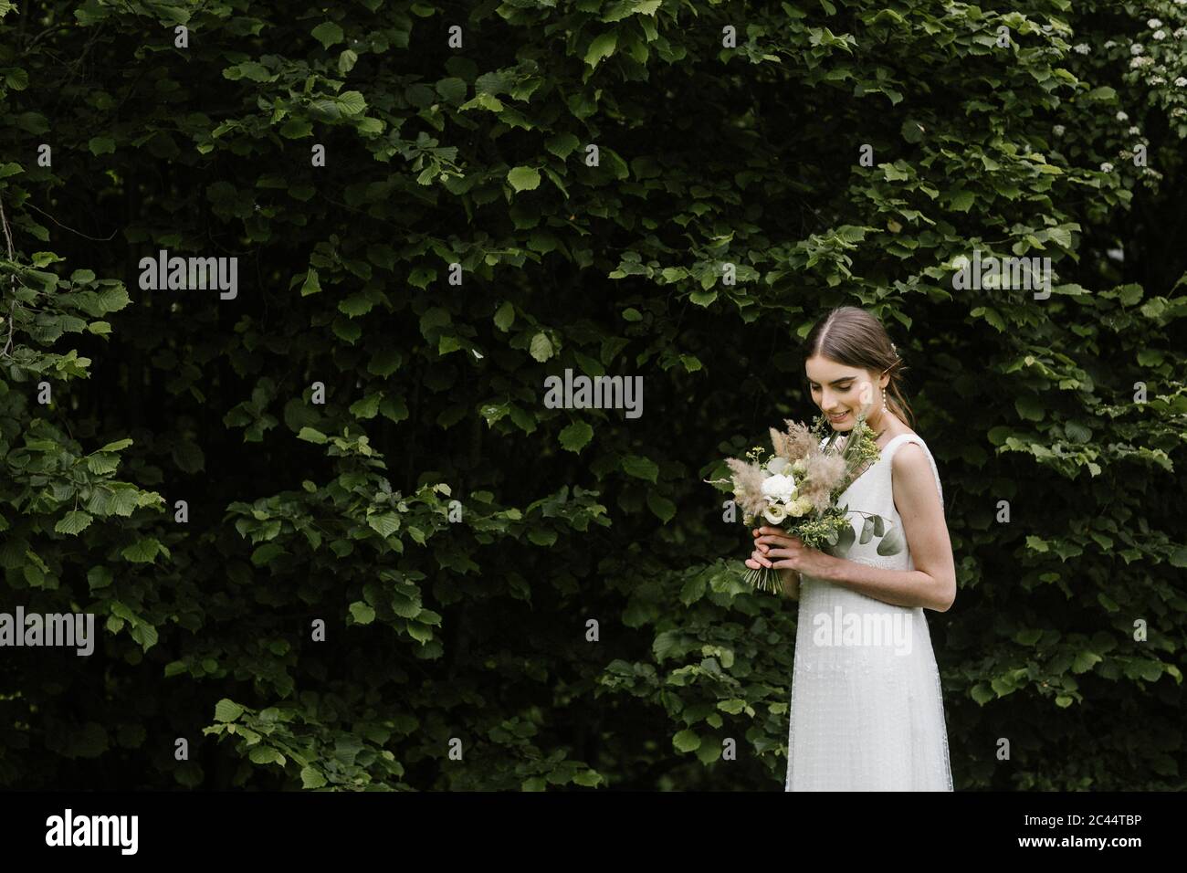 Jeune femme en robe de mariage élégante et bouquet Banque D'Images