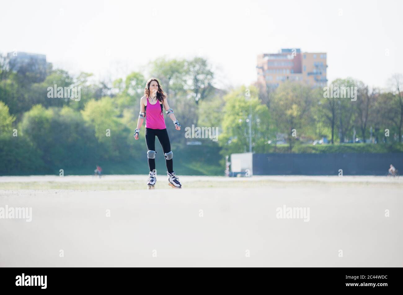 Jeune femme patineuse en ligne sur la terre dans le parc pendant la journée ensoleillée Banque D'Images