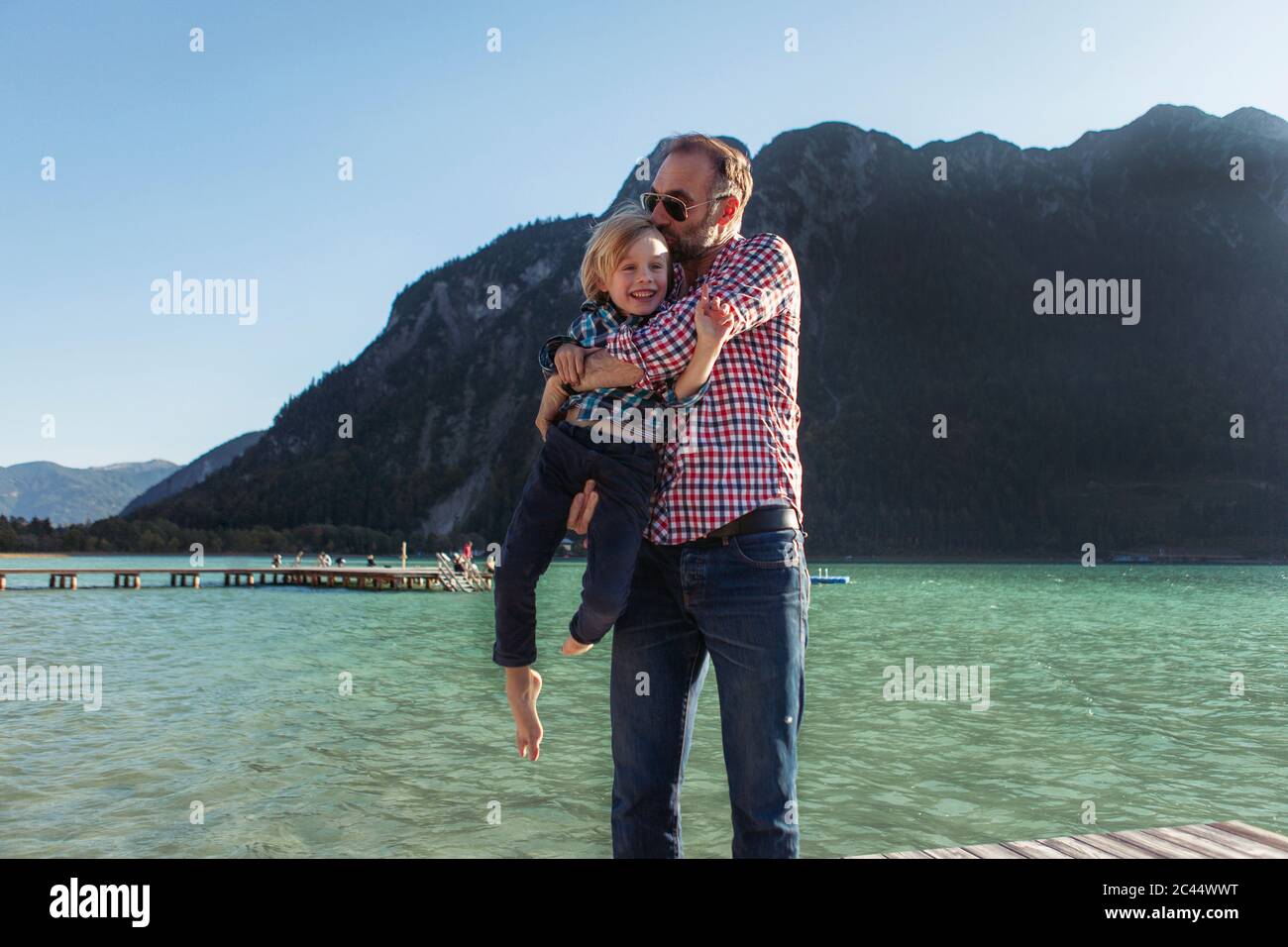 Père embrassant tout en portant son fils contre la montagne à Achensee, Tyrol, Autriche Banque D'Images