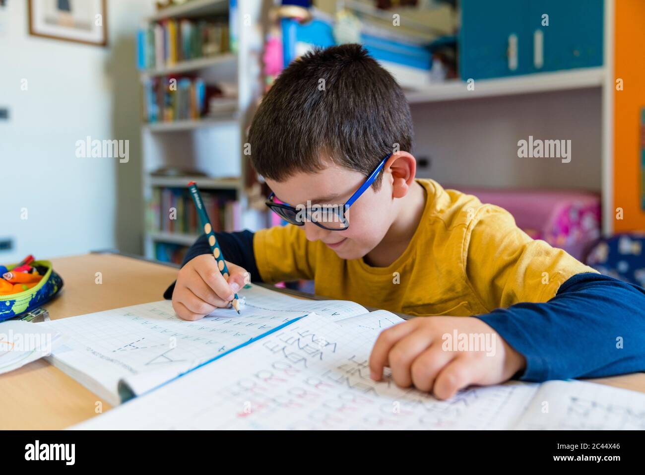 Apprentissage des élèves du primaire en étant assis au bureau pendant le Homeschooling Banque D'Images