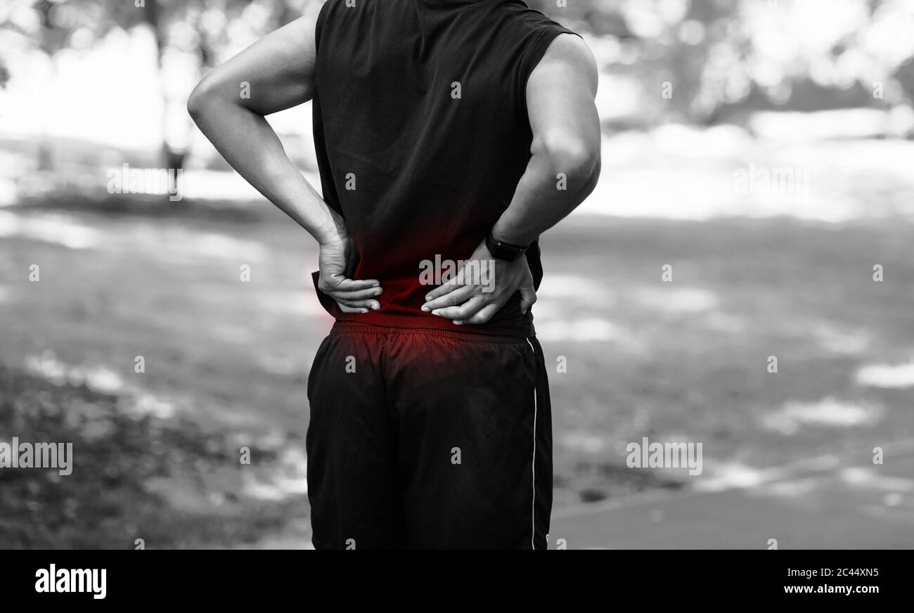 Vue rognée d'un jeune homme qui ressent des douleurs dans le dos lors de son entraînement au parc municipal, effet noir et blanc Banque D'Images