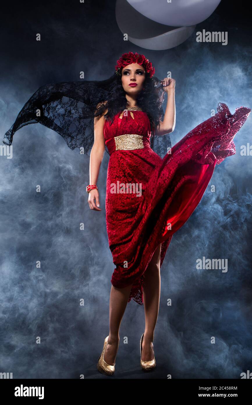 Sexy sorcière vêtue de robe rouge couverte de fumée Banque D'Images