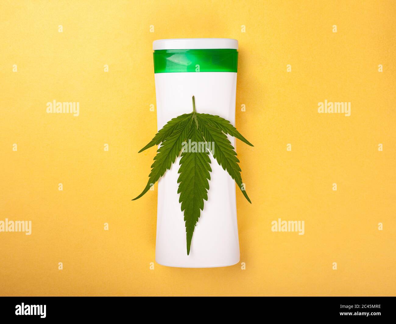 cosmétiques avec extrait de marijuana. soins de la peau, beauté, feuille de cannabis sur une bouteille blanche sur fond jaune vue du dessus. Banque D'Images