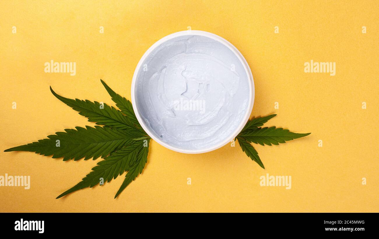 cosmétiques de soins de la peau avec extrait de marijuana, beauté, gommage corporel avec feuille de cannabis sur fond jaune vue du dessus. Banque D'Images