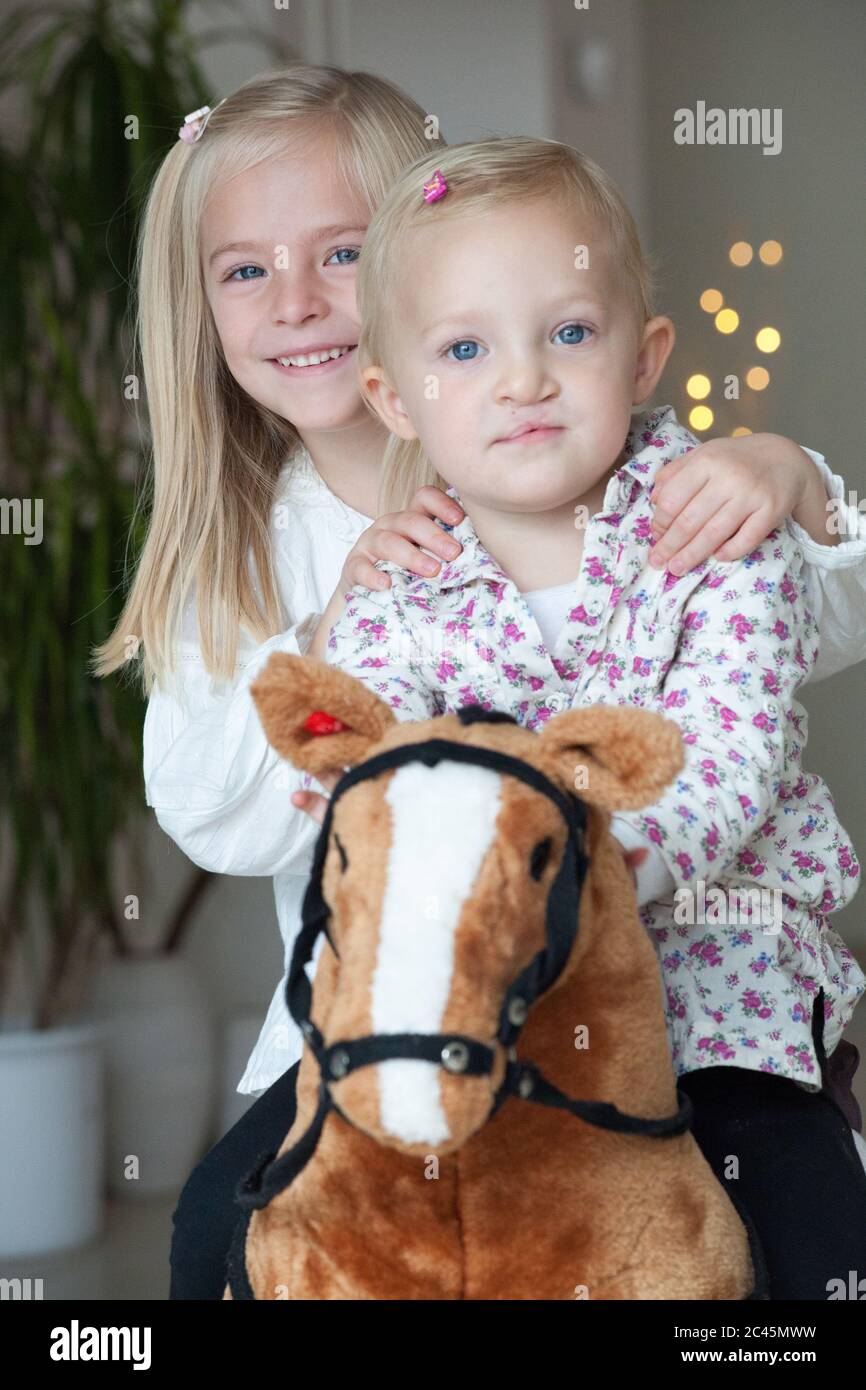 Deux sœurs blondes sur un cheval à bascule Banque D'Images