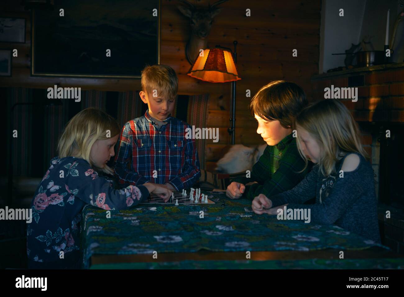 Groupe d'enfants assis à une table dans une cabane en rondins, jouant aux échecs, Vasterbotten LAN, Suède. Banque D'Images