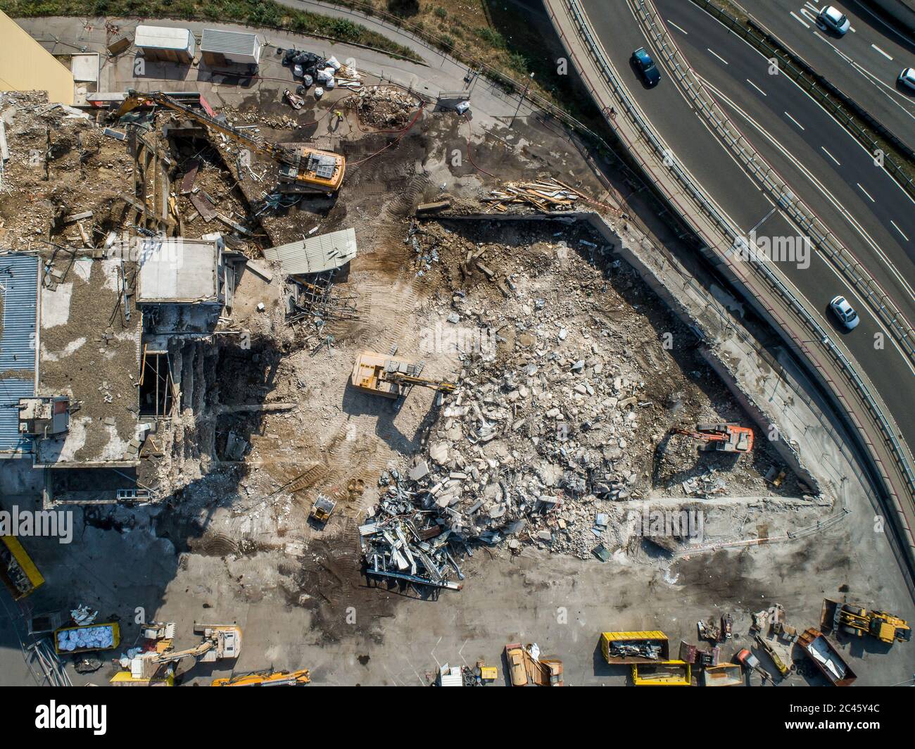 Vue aérienne du chantier de démolition et de construction de la pelle hydraulique avec machine à concaser hydraulique et conteneur jaune Banque D'Images